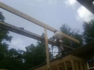 Carpenter setting a ridge beam over a new addition frame — Ice Dam Removal by Roofing Brothers in Dothan