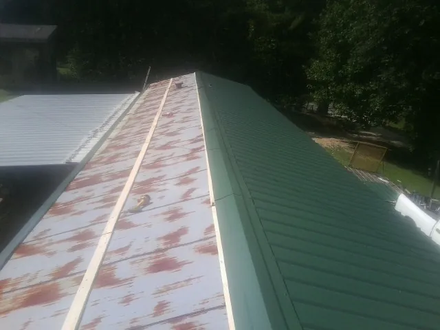 Old rusted panels beside newly installed green metal roofing — Wind Damage Roof Repair by Roofing Brothers in Dothan