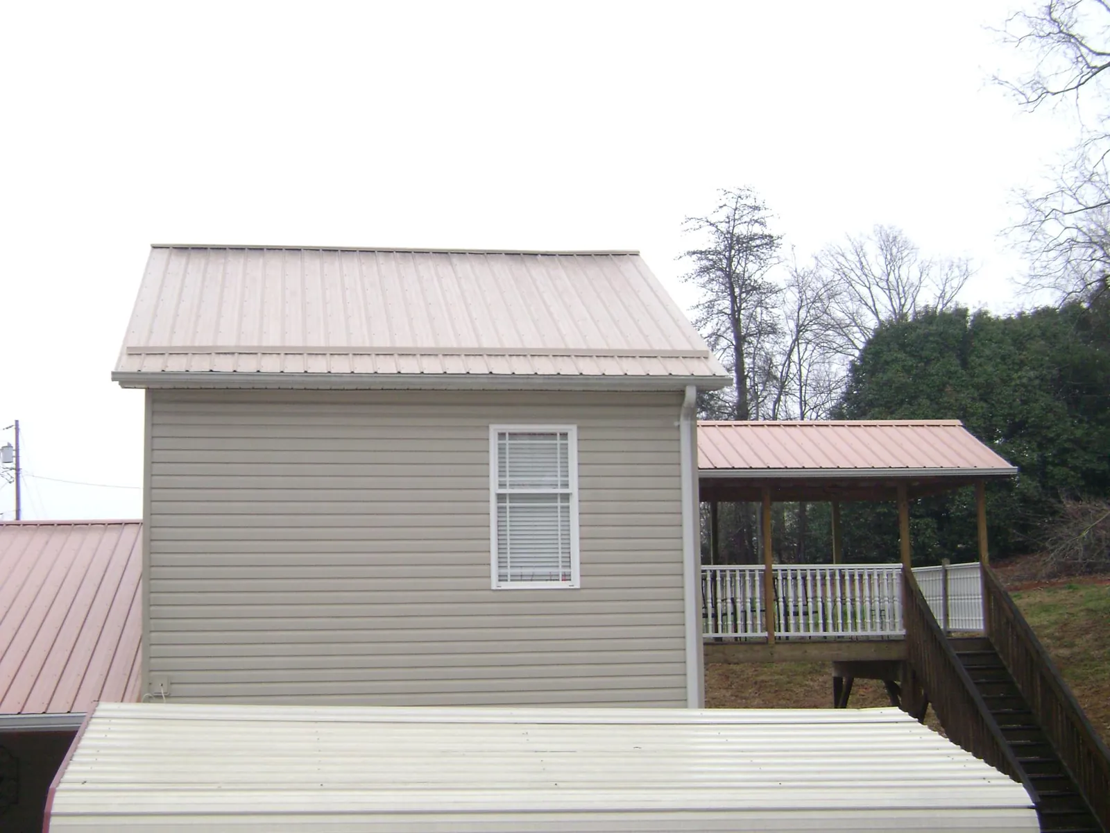 Tan metal roofs on a two story addition and attached porch, from a Roof Replacement job in Dothan
